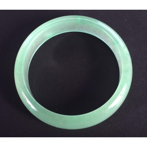 1299 - A CHINESE CARVED JADEITE BANGLE 20th Century. 7.25 cm wide.