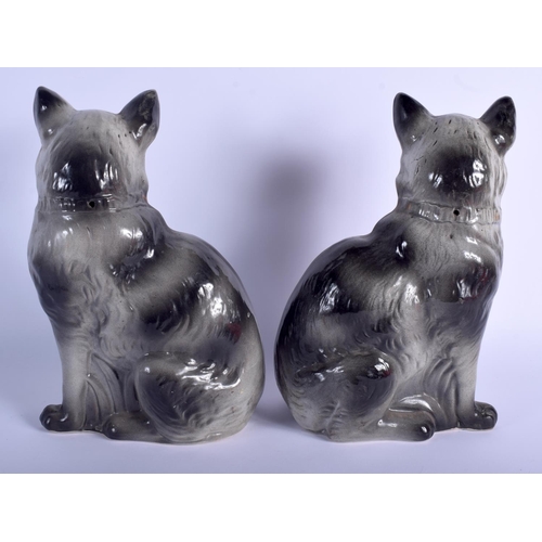 91 - A LARGE PAIR OF ANTIQUE CONTINENTAL POTTERY CATS modelled in gilt bows. 31 cm x 15 cm.