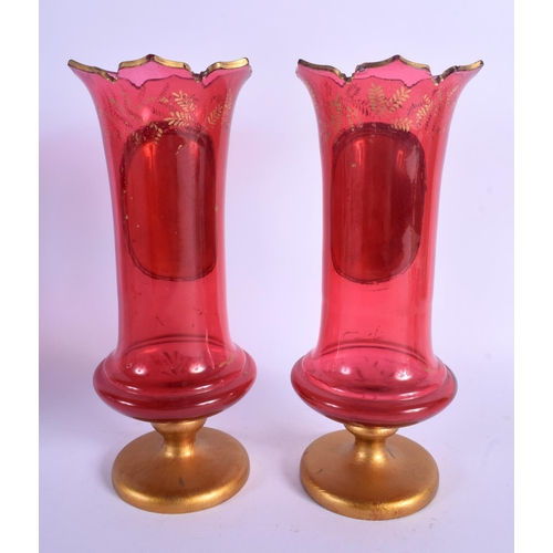 17 - A PAIR OF 19TH CENTURY BOHEMIAN RUBY GLASS VASES painted with girls within landscapes. 27 cm high.