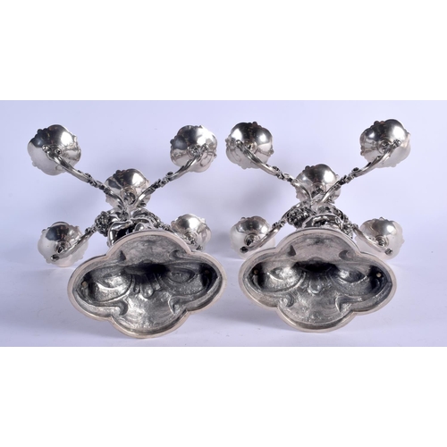 1157 - A LOVELY PAIR OF CONTINENTAL SILVER CANDLEABRA modelled two cherubs holding aloft floral capped scon... 