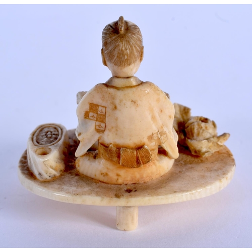 1554 - A 19TH CENTURY JAPANESE MEIJI PERIOD CARVED IVORY OKIMONO modelled as a male on a table. 5.5 cm x 5 ... 