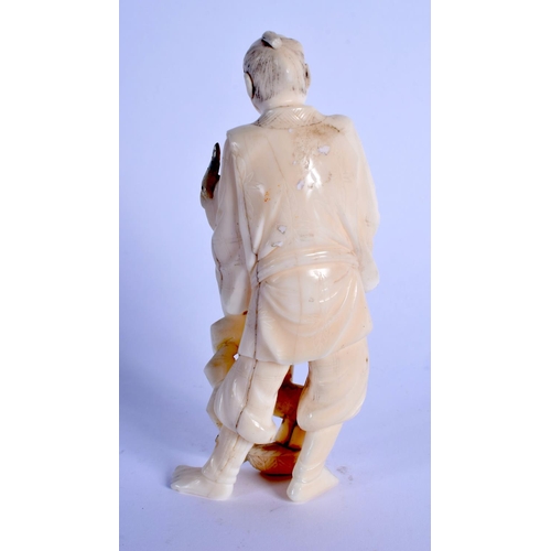 1578 - A LATE 19TH CENTURY JAPANESE MEIJI PERIOD CARVED IVORY OKIMONO modelled holding a mask. 11.5 cm high... 