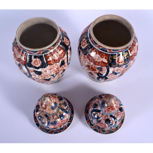 1734 - A PAIR OF 19TH CENTURY JAPANESE MEIJI PERIOD IMARI VASES AND COVERS of ribbed form. 30 cm high.