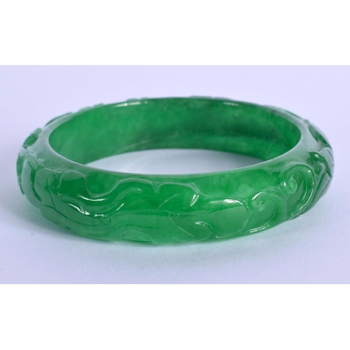 1948 - A CHINESE CARVED APPLE JADEITE BANGLE 20th Century. 7 cm wide.