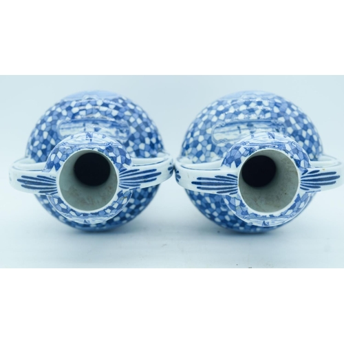 2822 - A pair of Delft twin handle vases painted with scenes of Dutch barges. 25cm.