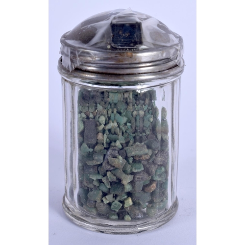 876 - A COLLECTION OF ROUGH CUT EMERALDS within a silver topped jar. (qty)