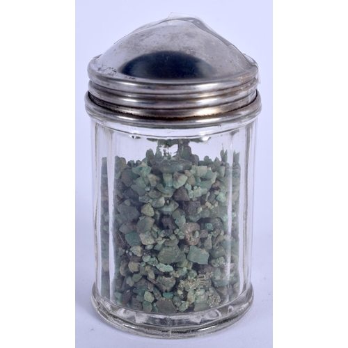 876 - A COLLECTION OF ROUGH CUT EMERALDS within a silver topped jar. (qty)