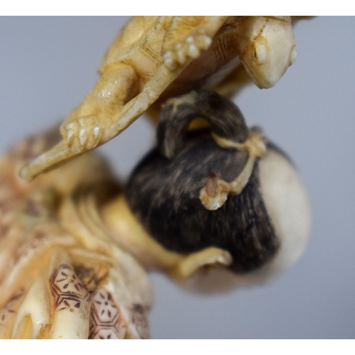 54 - A 19TH CENTURY JAPANESE MEIJI PERIOD CARVED IVORY OKIMONO modelled as a fisherman standing upon an o... 