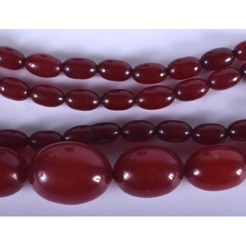 1042 - AN ART DECO CHERRY AMBER TYPE NECKLACE. 55 grams. 66 cm long, largest bead 3 cm x 2 cm.