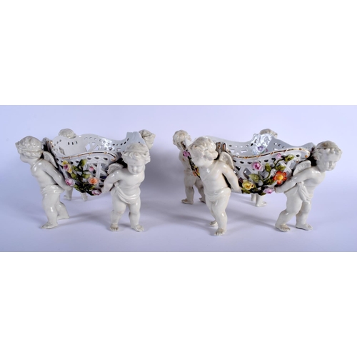 131 - A PAIR OF 19TH CENTURY GERMAN PORCELAIN OPENWORK FRUIT BASKETS modelled with four putti holding alof... 