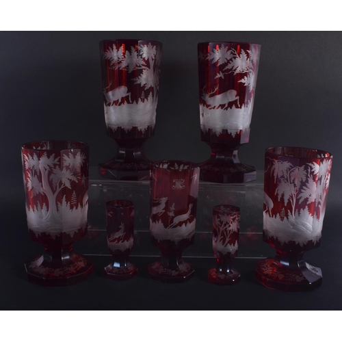 35 - SEVEN ANTIQUE BOHEMIAN RUBY GLASS GOBLET BEAKERS decorated with deer. Largest 18.5 cm high. (7)