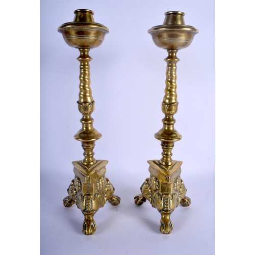 713 - A PAIR OF 18TH CENTURY BRASS ECCLESIASTICAL CANDLESTICKS decorated with mask heads. 39 cm high.