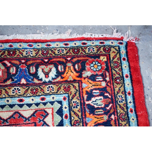 2601 - A LARGE MIDDLE EASTERN RED GROUND CARPET decorated with a blue lozenge of flowers. 354 cm x 264 cm.