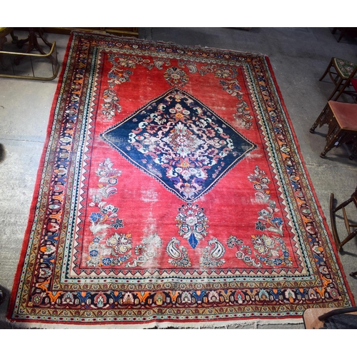 2601 - A LARGE MIDDLE EASTERN RED GROUND CARPET decorated with a blue lozenge of flowers. 354 cm x 264 cm.