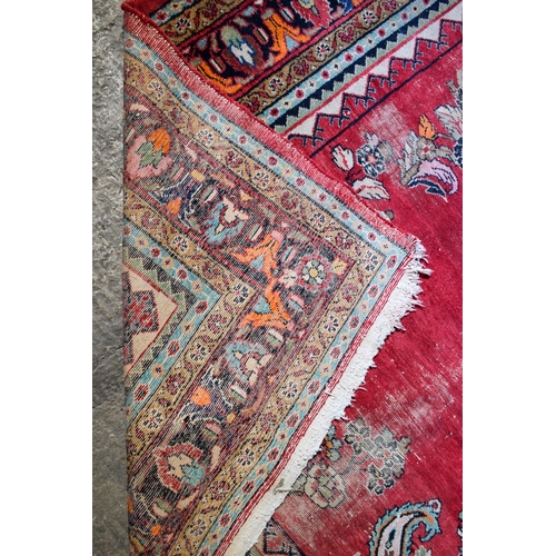 2601 - A LARGE MIDDLE EASTERN RED GROUND CARPET decorated with a blue lozenge of flowers. 354 cm x 264 cm.