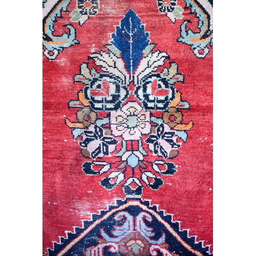 2601 - A LARGE MIDDLE EASTERN RED GROUND CARPET decorated with a blue lozenge of flowers. 354 cm x 264 cm.