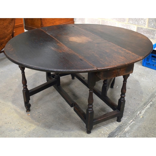 2569 - AN 18TH CENTURY OAK GATELEG DINING TABLE upon cylindrical supports. 118 cm x 70 cm extended.