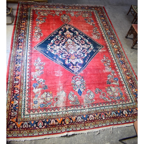2601 - A LARGE MIDDLE EASTERN RED GROUND CARPET decorated with a blue lozenge of flowers. 354 cm x 264 cm.