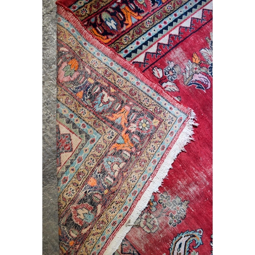 2601 - A LARGE MIDDLE EASTERN RED GROUND CARPET decorated with a blue lozenge of flowers. 354 cm x 264 cm.
