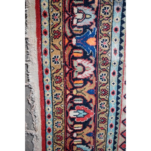 2601 - A LARGE MIDDLE EASTERN RED GROUND CARPET decorated with a blue lozenge of flowers. 354 cm x 264 cm.