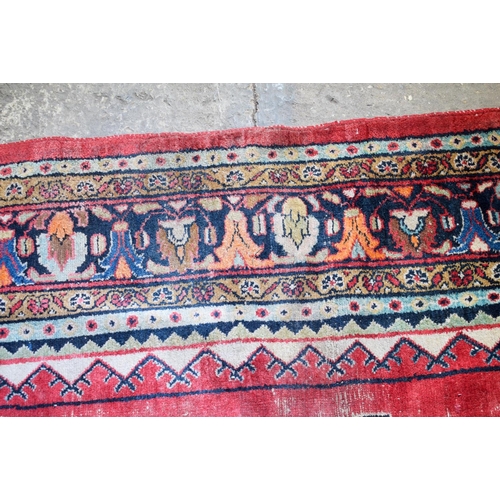 2601 - A LARGE MIDDLE EASTERN RED GROUND CARPET decorated with a blue lozenge of flowers. 354 cm x 264 cm.
