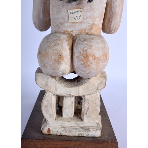372 - AN AFRICAN WHITE PAINTED TRIBAL CARVED WOOD FIGURE modelled upon a stool. 40 cm high.