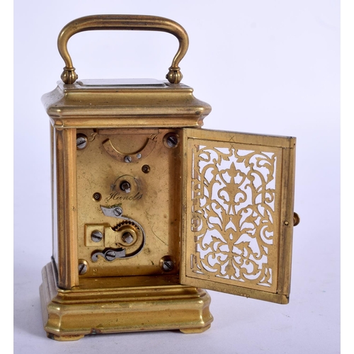 1084 - A MINIATURE BRASS CARRIAGE CLOCK.  7.4cm high (9.2cm with handle raised) x 5.1cm x 4cm