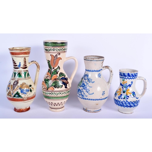 90 - FOUR EASTERN EUROPEAN TIN GLAZED POTTERY JUGS in various forms and sizes. Largest 25 cm high. (4)