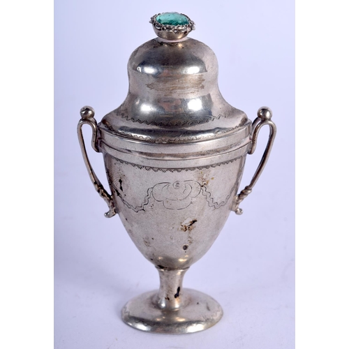 915 - AN ANTIQUE MINIATURE WHITE METAL URN AND COVER INSET WITH A GEM TOP.  8cm high, 5cm wide