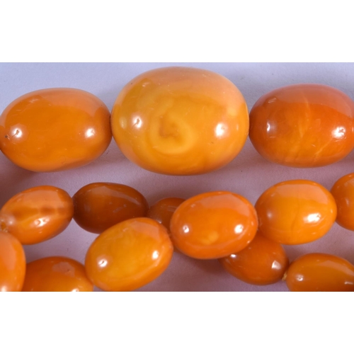 972 - AN AMBER NECKLACE.  65cm long, Largest bead 21 mm diameter, weight 59g