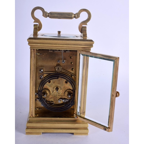 392 - A FRENCH REPEATING BRASS CARRIAGE CLOCK with enamelled dial. 15 cm high inc handle.