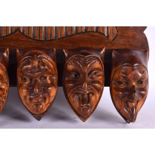 387 - A RARE EARLY 20TH CENTURY EUROPEAN CARVED WOOD WALL MOUNTED PIPE RACK formed as mischievous mask hea... 