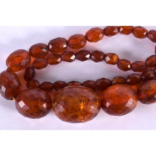 473 - A 1930S FACETTED AMBER NECKLACE. 54 cm long, largest bead 2.25 cm wide.