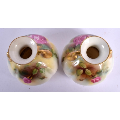 67 - A PAIR OF ROYAL WORCESTER TWIN HANDLED PORCELAIN VASES painted with roses. 9 cm x 6 cm.