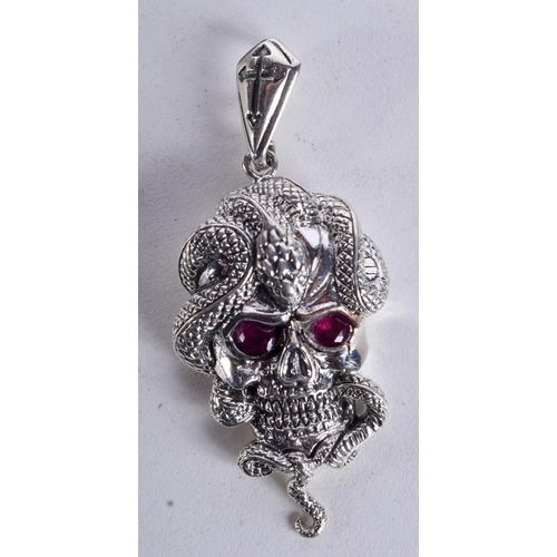 897 - A SKULL PENDANT WITH A SNAKE COILED AROUND THE HEAD WITH GEM SET EYES.  5.7cm x 2.4cm