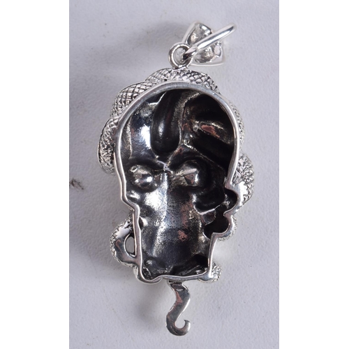 897 - A SKULL PENDANT WITH A SNAKE COILED AROUND THE HEAD WITH GEM SET EYES.  5.7cm x 2.4cm