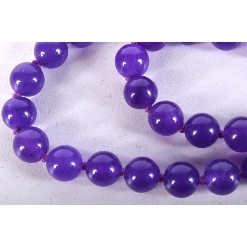 934 - A STRING OF AMETHYST TYPE BEADS.  Length 68cm, bead size 8mm