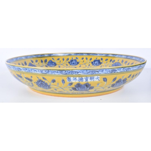 3162 - A large Chinese porcelain yellow ground glazed dish decorated with fish and algae. 34cm.