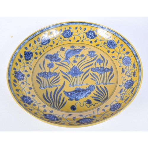 3162 - A large Chinese porcelain yellow ground glazed dish decorated with fish and algae. 34cm.