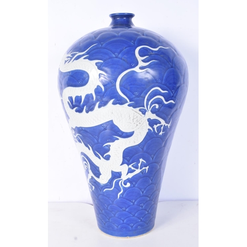 3188 - A large Chinese porcelain sacrificial blue Meiping vase decorated in relief with dragons and clouds.... 