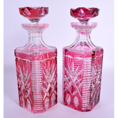36 - A PAIR OF BOHEMIAN RUBY FLASH DECANTERS AND STOPPERS with star curt decoration. 25 cm x 8 cm.