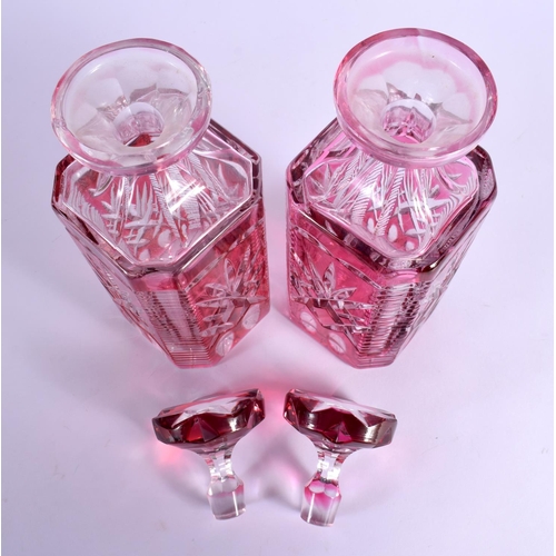 36 - A PAIR OF BOHEMIAN RUBY FLASH DECANTERS AND STOPPERS with star curt decoration. 25 cm x 8 cm.