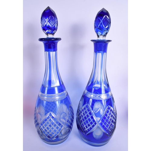 57 - A PAIR OF BOHEMIAN BLUE FLASH DECANTERS with stoppers  together with a vase & bells. Largest 34 cm h... 