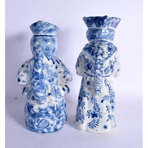 42 - A LARGE PAIR OF ANTIQUE DELFT BLUE AND WHITE CHARACTER TOBY JUGS painted with motifs. 27 cm x 14 cm.