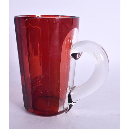 58 - AN ANTIQUE GERMAN RUBY BOHEMIAN GLASS MUG engraved with buildings. 11.5 cm high.