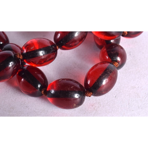 1256 - A STRING OF CHERRY COLOURED BEADS.  62cm long, weight 65g