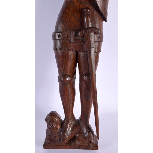 293D - AN ARTS AND CRAFTS CARVED WOOD FIGURE OF A SOLDIER modelled standing upon a lion. 45 cm high.