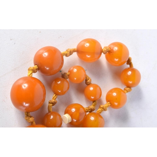 1032 - AN AMBER TYPE NECKLACE. 38 grams. 50 cm long, largest bead 1.5 cm wide.