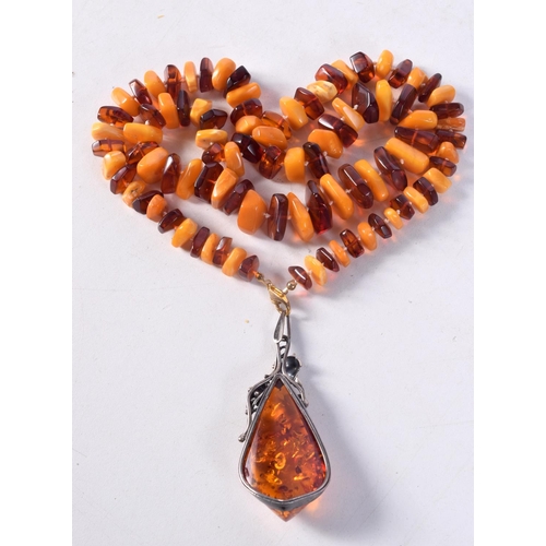 1260 - A SILVER BROOCH and an amber necklace. Necklace 70 cm long, pendant 7.75 cm x 3 cm. (2)