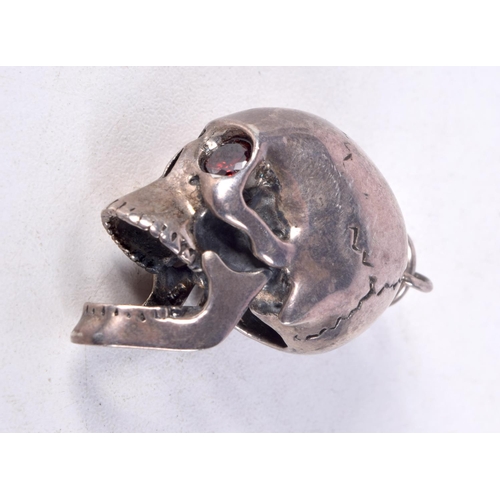 835 - A WHITE METAL SKULL PENDANT WITH GEM SET EYES AND AN ARTICULATED JAW.  3cm x 2.8cm x 2cm